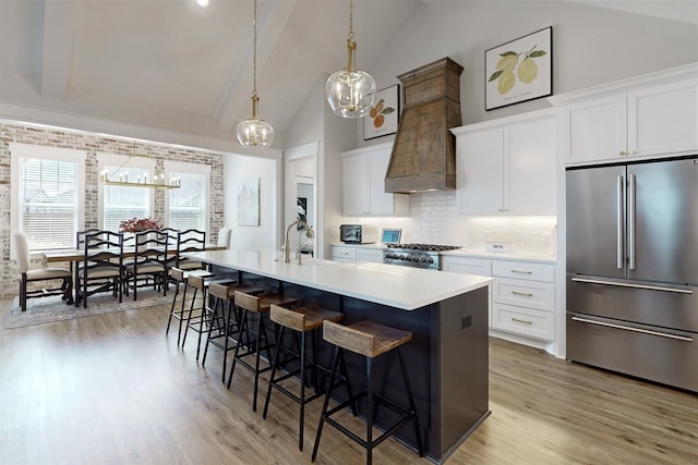 kitchen featuring white cabinetry, a kitchen island with sink, high quality fridge, and tasteful backsplash