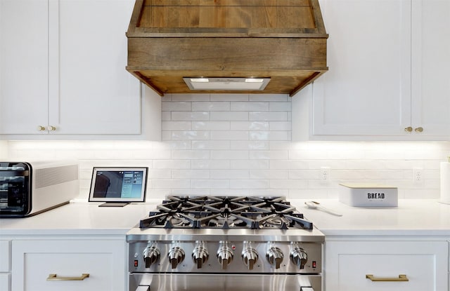 kitchen with white cabinets, custom range hood, backsplash, and high end stove