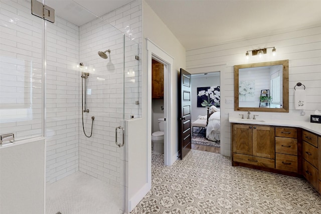 bathroom with vanity, wood walls, toilet, and a shower with shower door