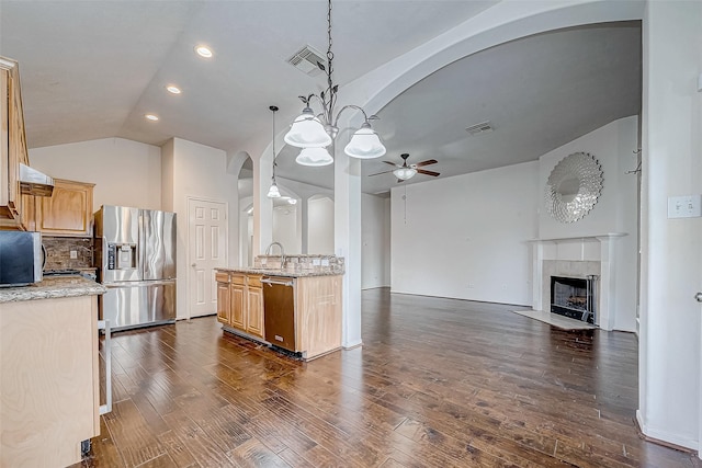 kitchen featuring pendant lighting, backsplash, ceiling fan with notable chandelier, light stone counters, and stainless steel appliances