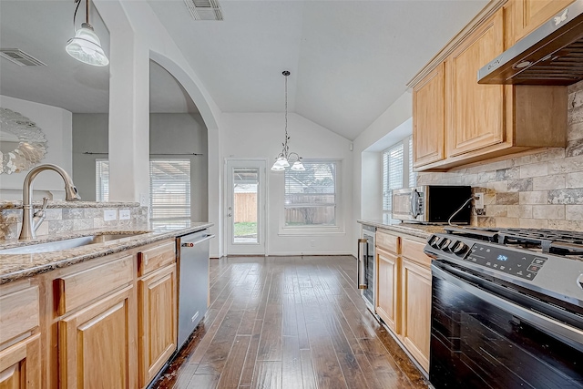 kitchen featuring appliances with stainless steel finishes, extractor fan, sink, light brown cabinets, and a chandelier