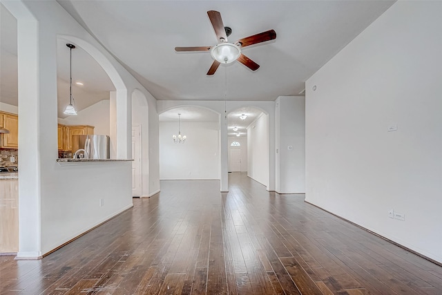 unfurnished living room with ceiling fan with notable chandelier, dark hardwood / wood-style flooring, and lofted ceiling