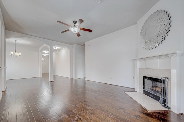 unfurnished living room featuring hardwood / wood-style floors, ceiling fan with notable chandelier, and a tiled fireplace