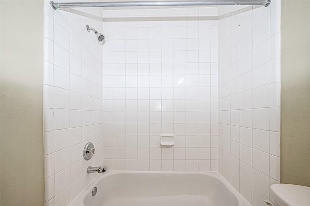 bathroom featuring toilet and tiled shower / bath