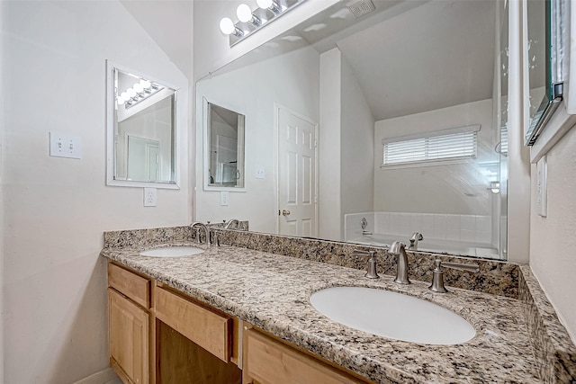 bathroom with a bathing tub, vanity, and vaulted ceiling