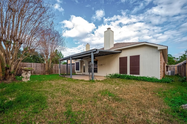 rear view of property featuring a lawn, cooling unit, and a patio area