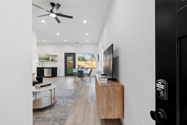 living room featuring ceiling fan, sink, and wood-type flooring