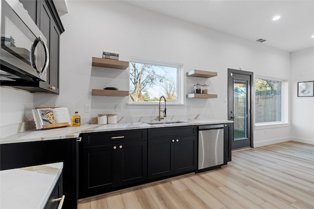 kitchen featuring light stone counters, sink, stainless steel appliances, and light wood-type flooring