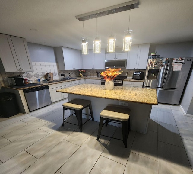 kitchen with light stone countertops, appliances with stainless steel finishes, a breakfast bar, pendant lighting, and a kitchen island