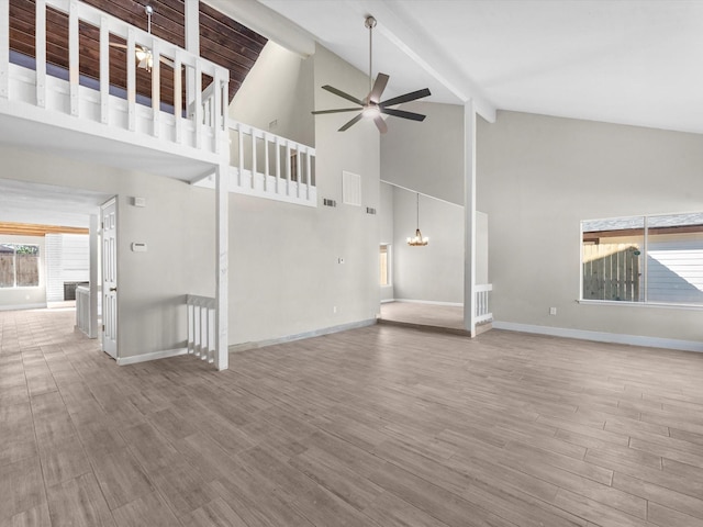 unfurnished living room featuring hardwood / wood-style floors, high vaulted ceiling, ceiling fan, and beam ceiling