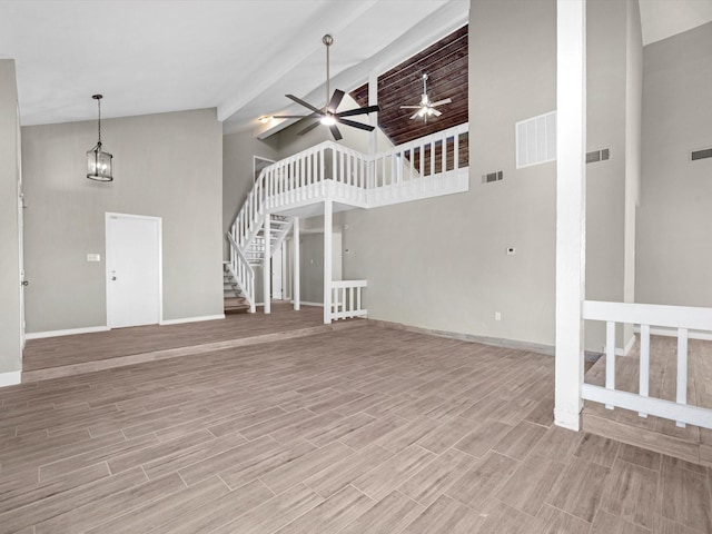 unfurnished living room with high vaulted ceiling and ceiling fan with notable chandelier