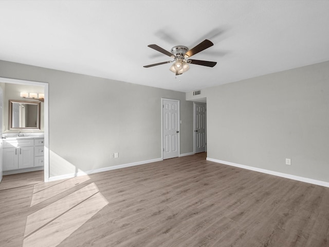 unfurnished bedroom featuring ceiling fan, light wood-type flooring, sink, and connected bathroom