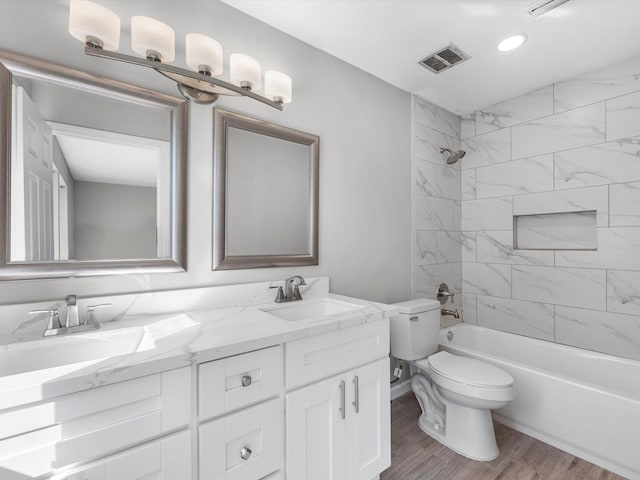 full bathroom with hardwood / wood-style floors, tiled shower / bath combo, toilet, and vanity