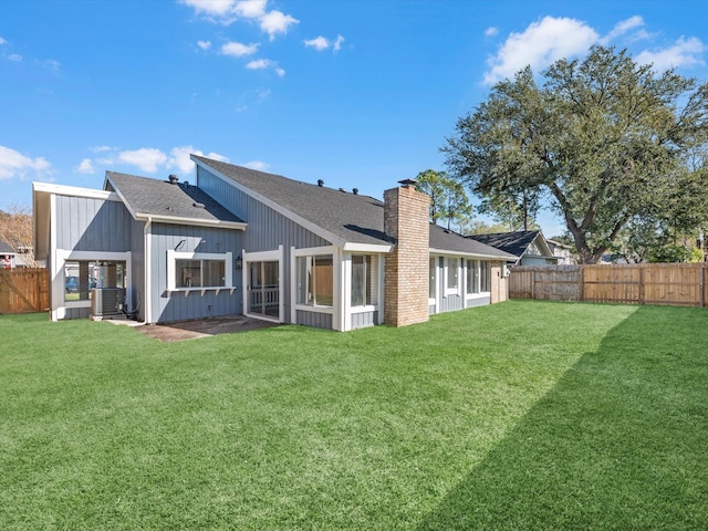 rear view of house featuring a sunroom, cooling unit, and a lawn