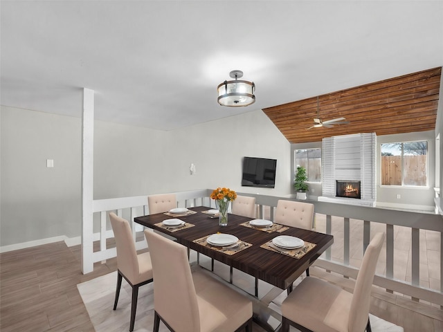 dining area with wood-type flooring, a brick fireplace, ceiling fan, and wood ceiling