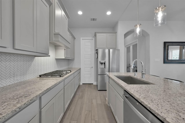 kitchen featuring pendant lighting, sink, appliances with stainless steel finishes, light stone counters, and white cabinetry