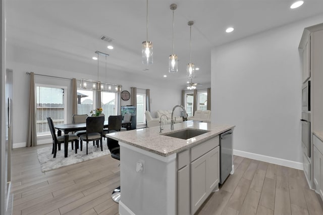 kitchen with ceiling fan, sink, stainless steel appliances, decorative light fixtures, and a kitchen island with sink