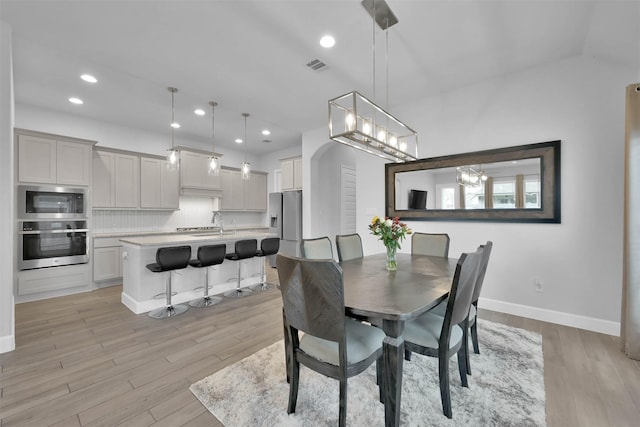 dining area featuring light hardwood / wood-style flooring, a chandelier, and sink