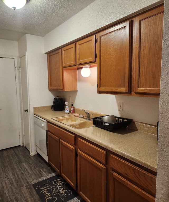 kitchen with dark wood-type flooring, dishwasher, sink, and a textured ceiling