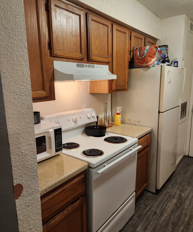 kitchen featuring dark hardwood / wood-style flooring, white appliances, and a textured ceiling