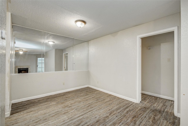 9797 Leawood Blvd Unit 903, Houston, TX 77099 - unfurnished room with wood finished floors, a textured ceiling, a fireplace, baseboards, and ceiling fan