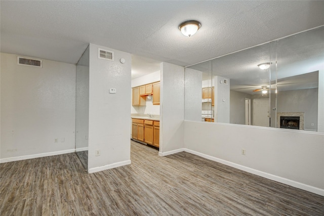 9797 Leawood Blvd Unit 903, Houston, TX 77099 - unfurnished living room featuring wood finished floors, a fireplace, a textured ceiling, a ceiling fan, and baseboards