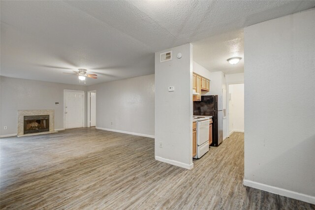 9797 Leawood Blvd Unit 903, Houston, TX 77099 - unfurnished living room featuring baseboards, light wood-type flooring, ceiling fan, a fireplace, and a textured ceiling