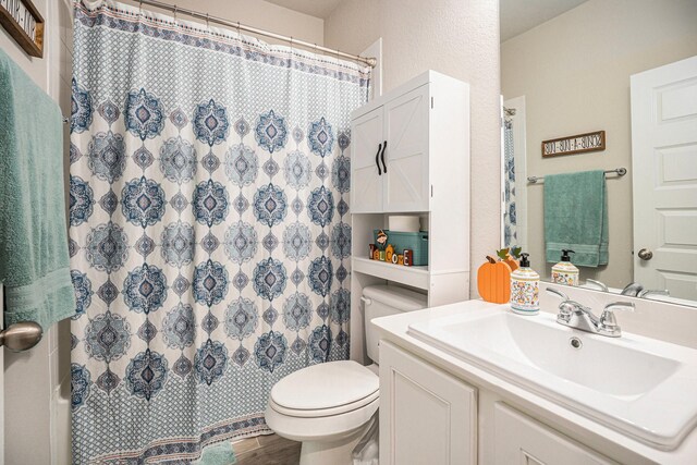 bathroom with wood-type flooring, toilet, curtained shower, and vanity