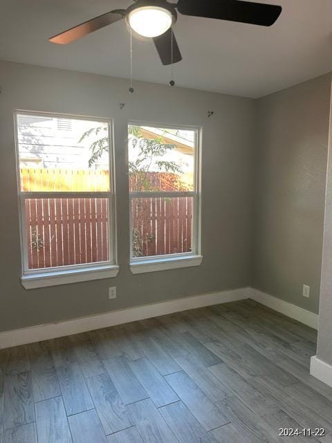 empty room with ceiling fan, light hardwood / wood-style flooring, and a healthy amount of sunlight