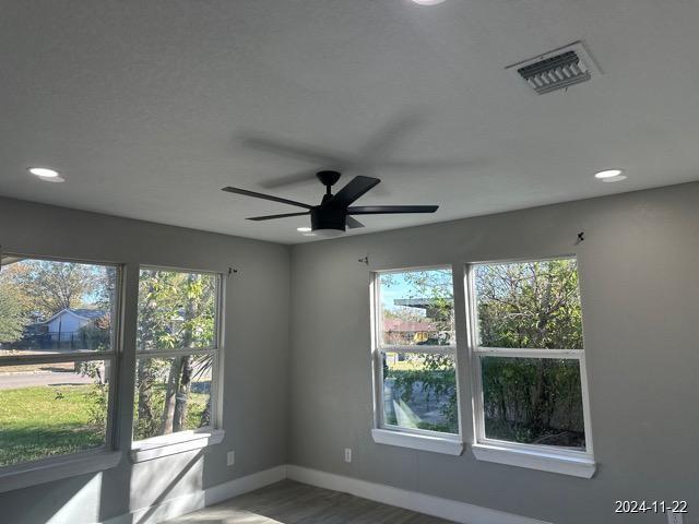 spare room featuring hardwood / wood-style floors, ceiling fan, and a healthy amount of sunlight