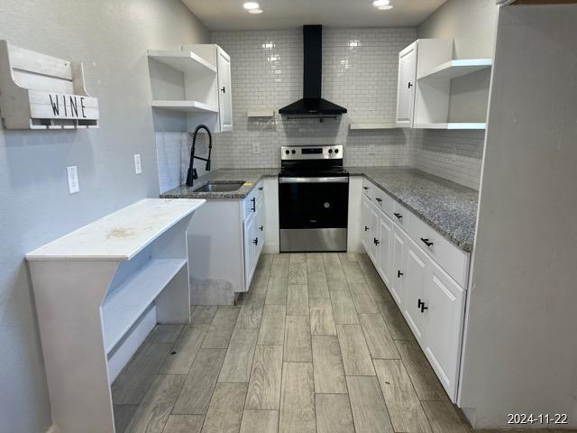 kitchen with white cabinetry, wall chimney exhaust hood, stainless steel range with electric cooktop, and sink