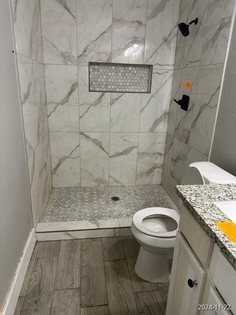 bathroom featuring tiled shower, vanity, and toilet