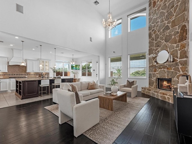 living room with a fireplace, an inviting chandelier, a healthy amount of sunlight, and dark hardwood / wood-style floors