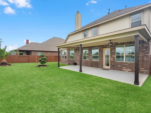 rear view of house with ceiling fan, a patio, and a yard