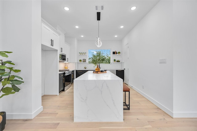 kitchen with a center island, open shelves, visible vents, appliances with stainless steel finishes, and white cabinetry