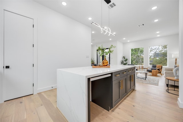 kitchen with a center island, pendant lighting, visible vents, light wood-style floors, and open floor plan