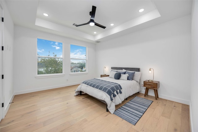 bedroom with recessed lighting, a raised ceiling, a ceiling fan, light wood-type flooring, and baseboards