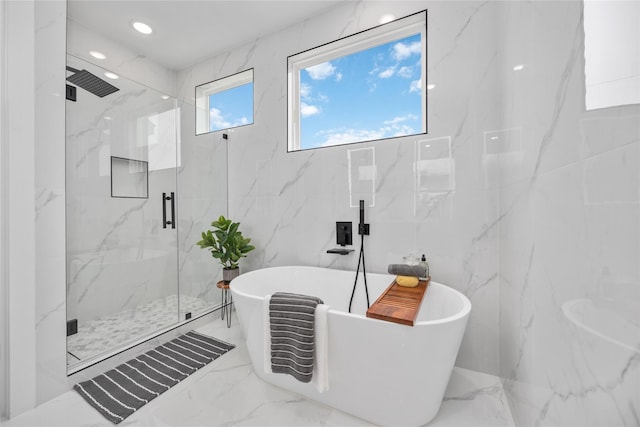 bathroom featuring stone wall, recessed lighting, a freestanding bath, marble finish floor, and a marble finish shower