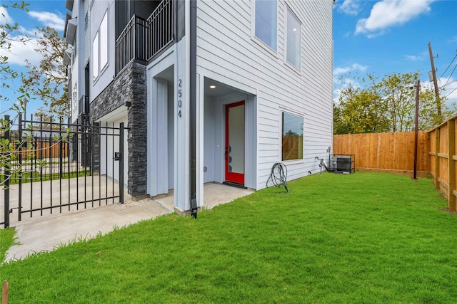 view of side of property featuring a fenced backyard, a yard, and central AC unit