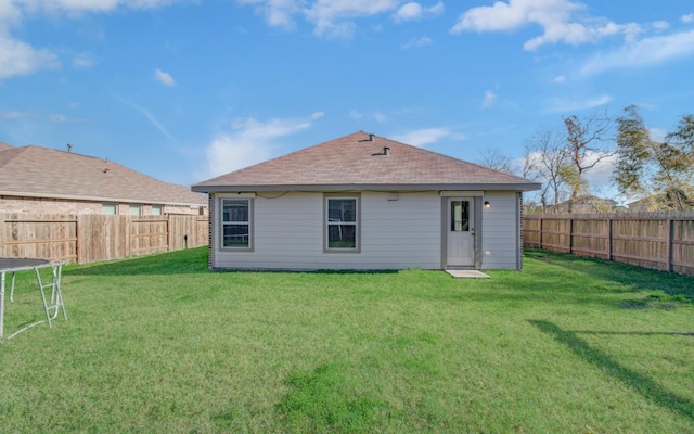 back of house featuring a trampoline and a lawn