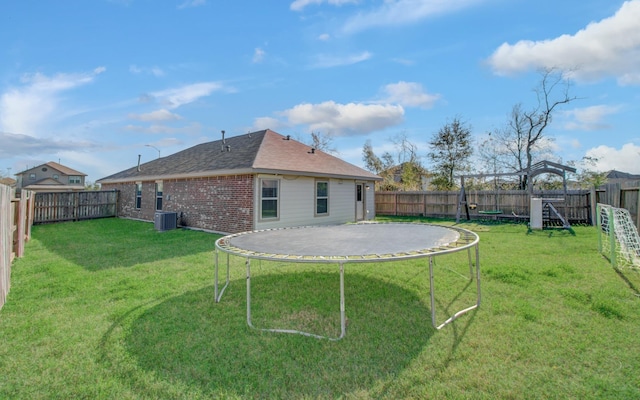 back of property featuring a yard, a trampoline, and central air condition unit