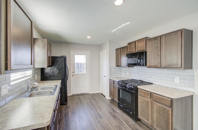 kitchen featuring tasteful backsplash, sink, black appliances, and wood-type flooring