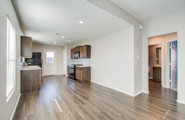 kitchen with sink, tasteful backsplash, hardwood / wood-style flooring, and black appliances