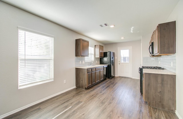 kitchen with decorative backsplash, sink, black appliances, and hardwood / wood-style flooring