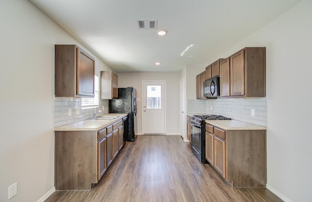 kitchen featuring black appliances, dark hardwood / wood-style floors, decorative backsplash, and sink