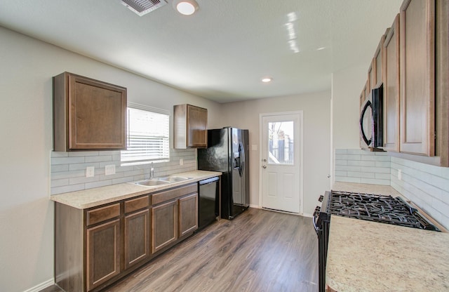 kitchen with tasteful backsplash, dark hardwood / wood-style floors, black appliances, and sink