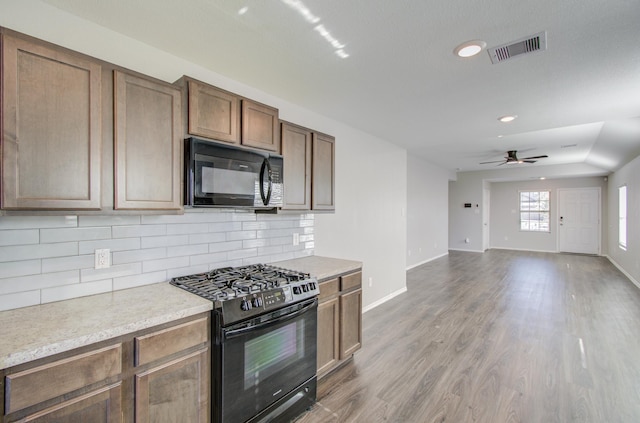 kitchen featuring tasteful backsplash, ceiling fan, hardwood / wood-style floors, and black appliances