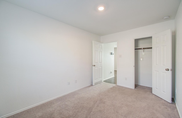 unfurnished bedroom with a closet and light colored carpet