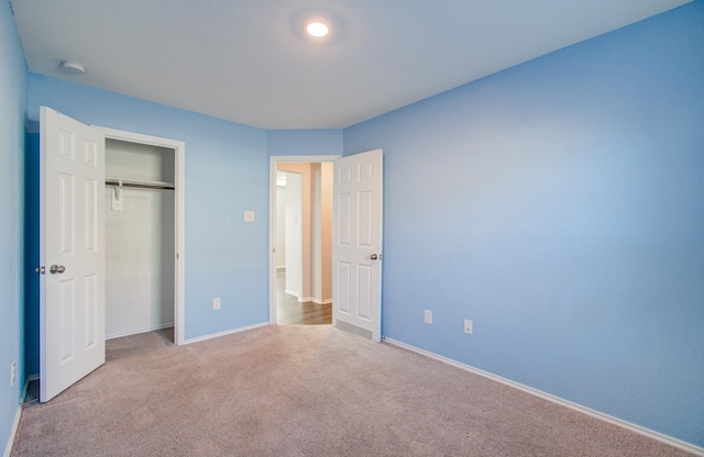 unfurnished bedroom with light colored carpet and a closet