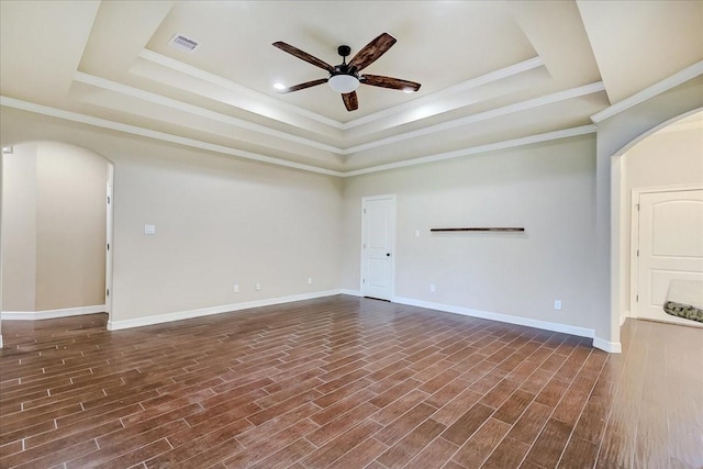 spare room featuring a tray ceiling, crown molding, ceiling fan, and dark wood-type flooring